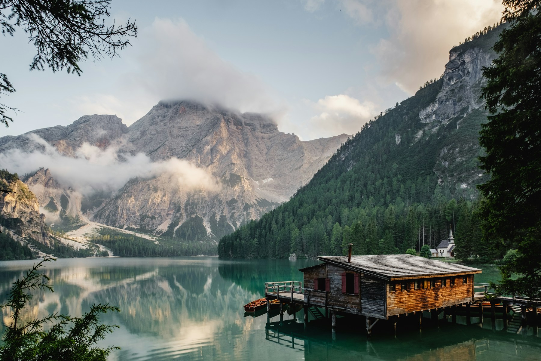 Still lake reflecting mountains and trees beneath an open sky